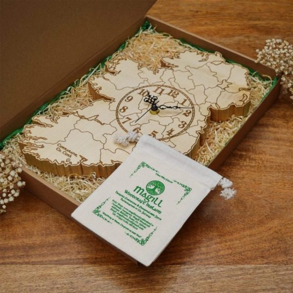 A personalised map of Ireland clock in an Irish gift box, handmade by Magill Woodcraft Ireland, sits on a wood table top.
