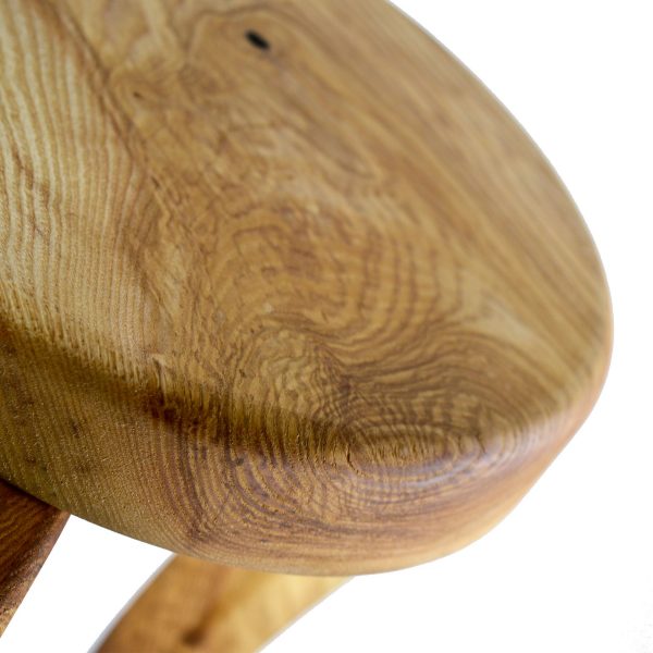 Close up of a handmade 3 legged wooden stool made from native Irish Ash wood on a white background. The seat is round and woodturned. The legs are in the Queen Ann style. The stool is about 12" tall x 10" in diameter.