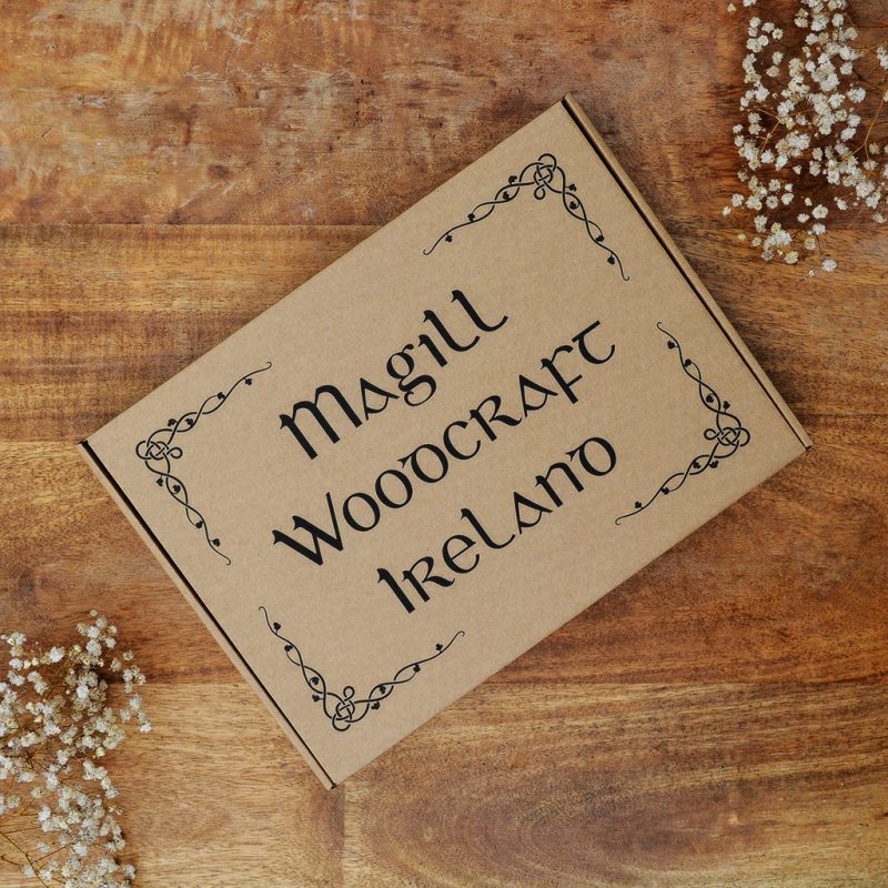 Lidded cardboard gift box with Magill Woodcraft Ireland Irish font printed on a wooden table. For wooden map of Ireland product.